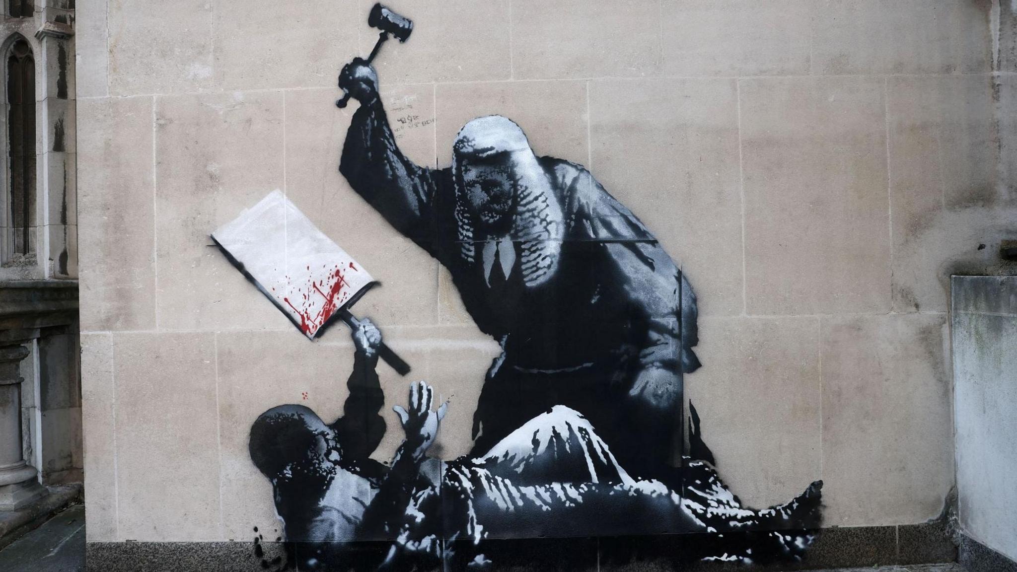 A robed figure raises a gavel over a fallen protester from the mural 'Judge'